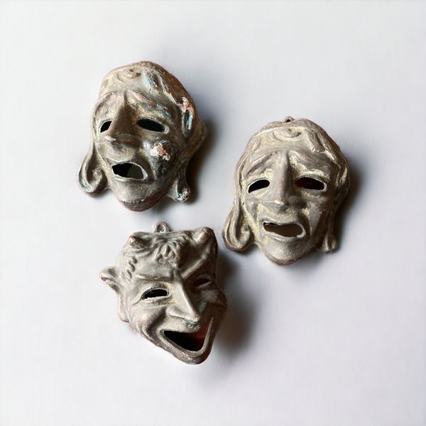 Tre piccole maschere in metallo brunito